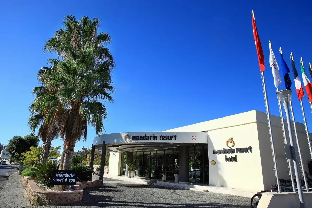 Wejście do Mandarin Resort Hotel z palmami i flagami. Wiele pozytywnych mandarin resort opinie potwierdza jego urok.