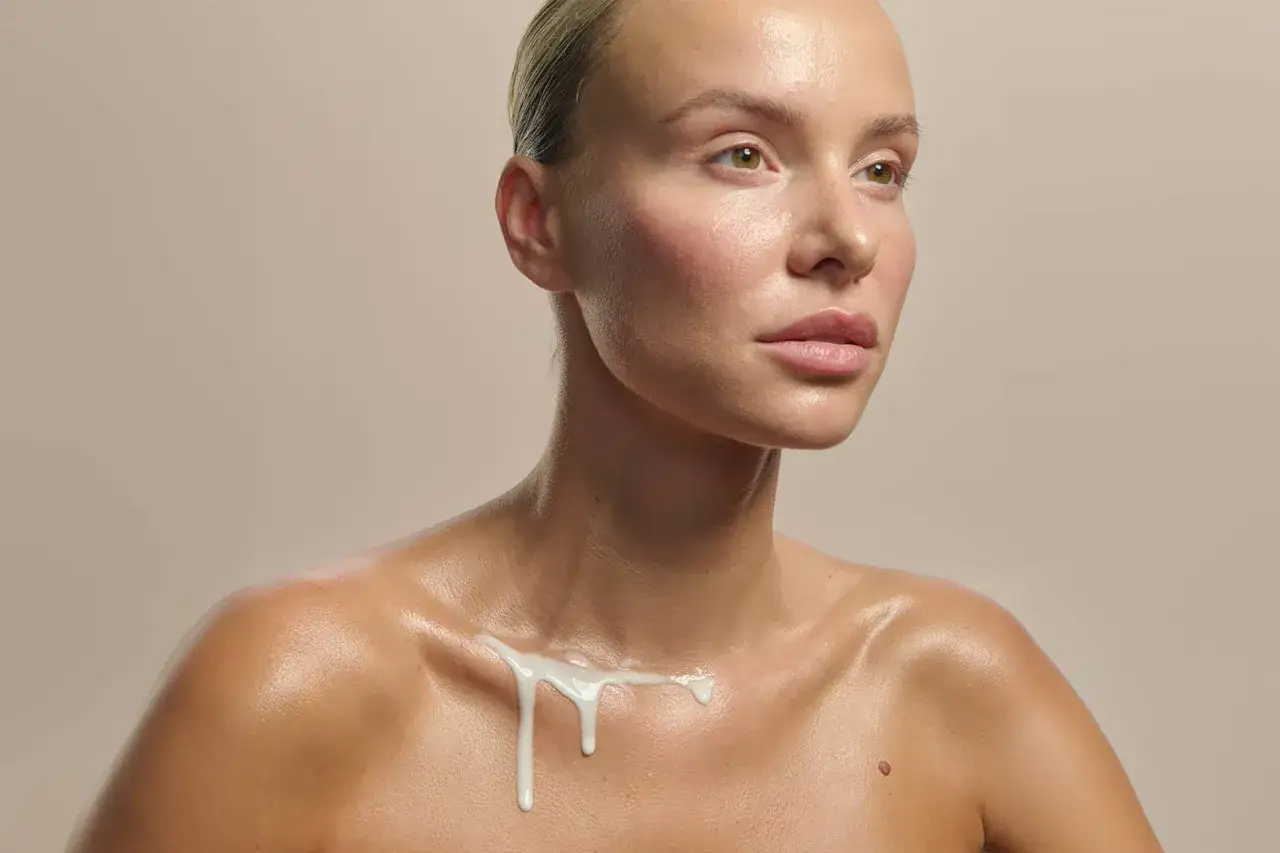 Kobieta z błyszczącą skórą, na której spływa biała substancja, przypominająca naturalny sebum.