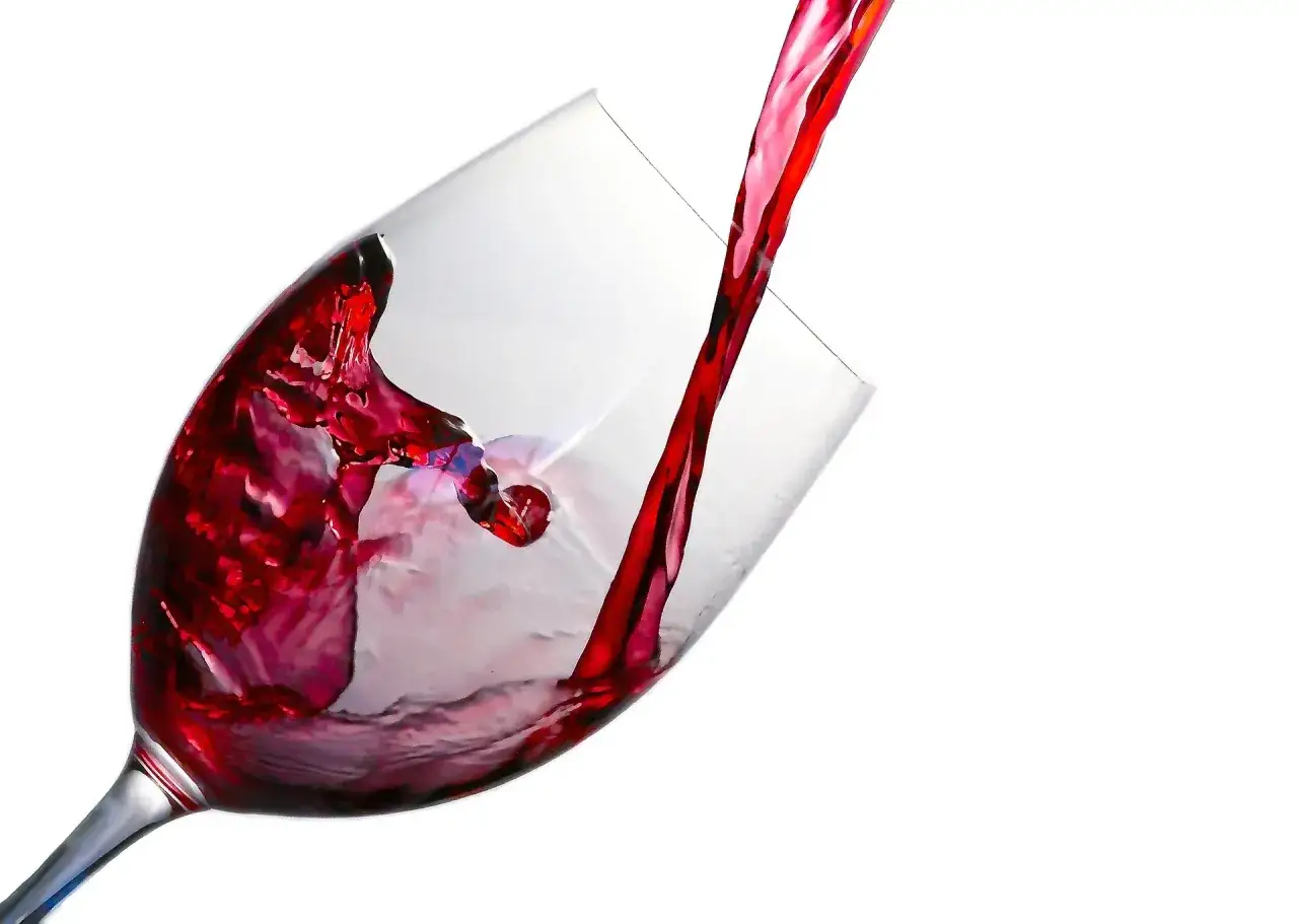 Un jet de vin rouge tourbillonne dans un verre à beaujolais, créant des éclaboussures vibrantes.