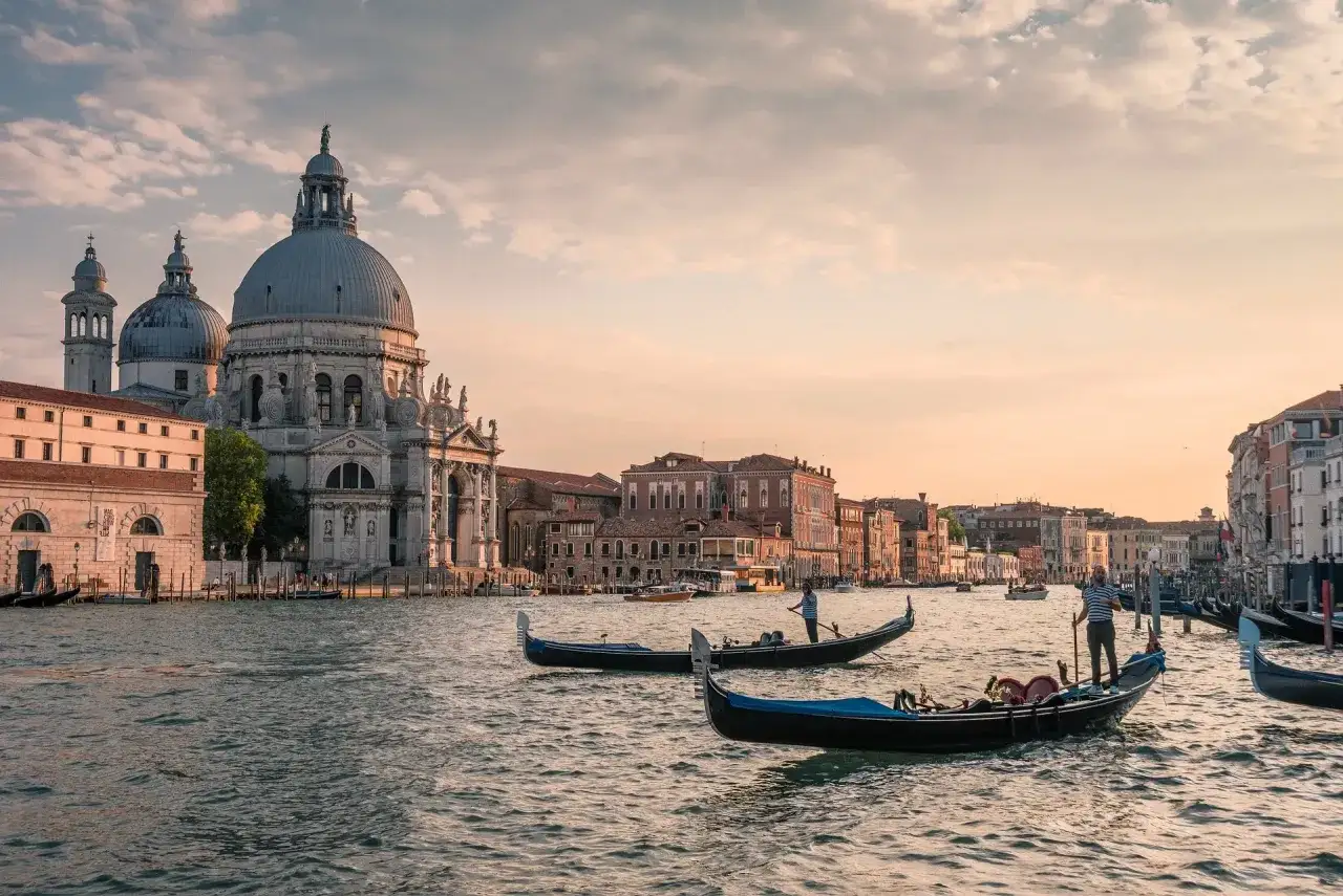 Wenecja w jeden dzień: gondole płynące po Canale Grande przy Bazylice Santa Maria della Salute w złotym świetle zachodzącego słońca.