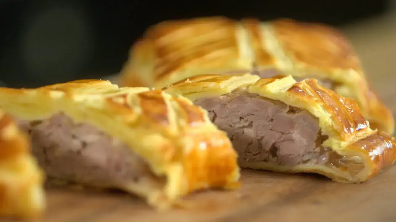 Tranche d'un plat lorrain, une viande savoureuse enveloppée dans une pâte feuilletée dorée.