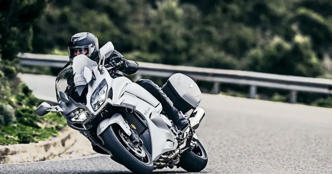 Motocyklista w kasku pochyla się na białym motocyklu Yamaha FJR 1300, pokonując zakręt. Dane techniczne tego modelu są imponujące.