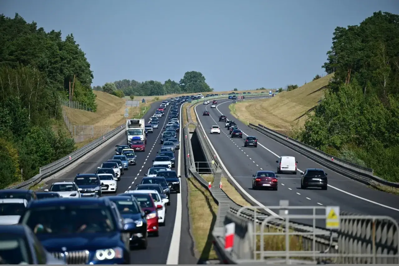 Korek samochodów na autostradzie A1, zieleń po bokach, błękitne niebo.