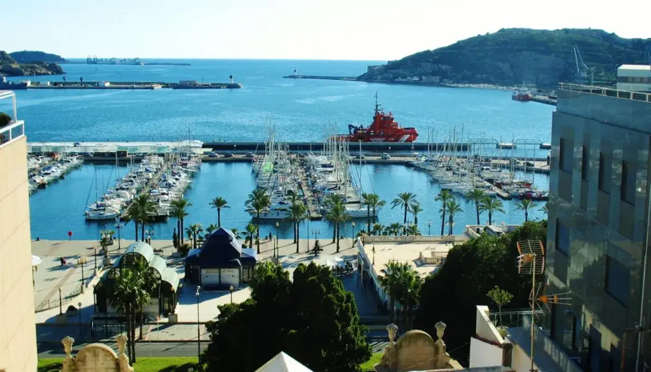 Der Cartagena Hafen mit vielen Segelbooten und einem roten Rettungsboot. Palmen säumen die Promenade.