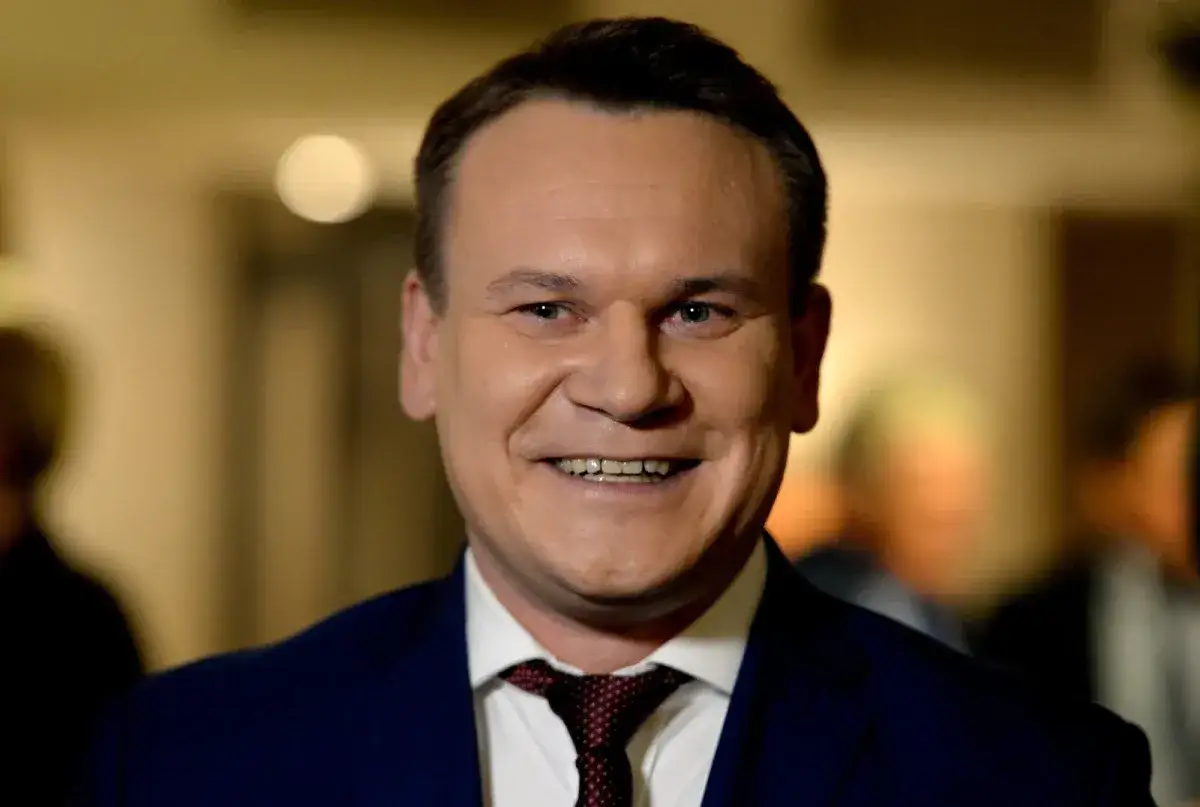 Uśmiechnięty mężczyzna w garniturze, z krawatem. Czy Tarczyński jest żonaty? To pytanie, na które odpowiedź może być ukryta w jego spojrzeniu.