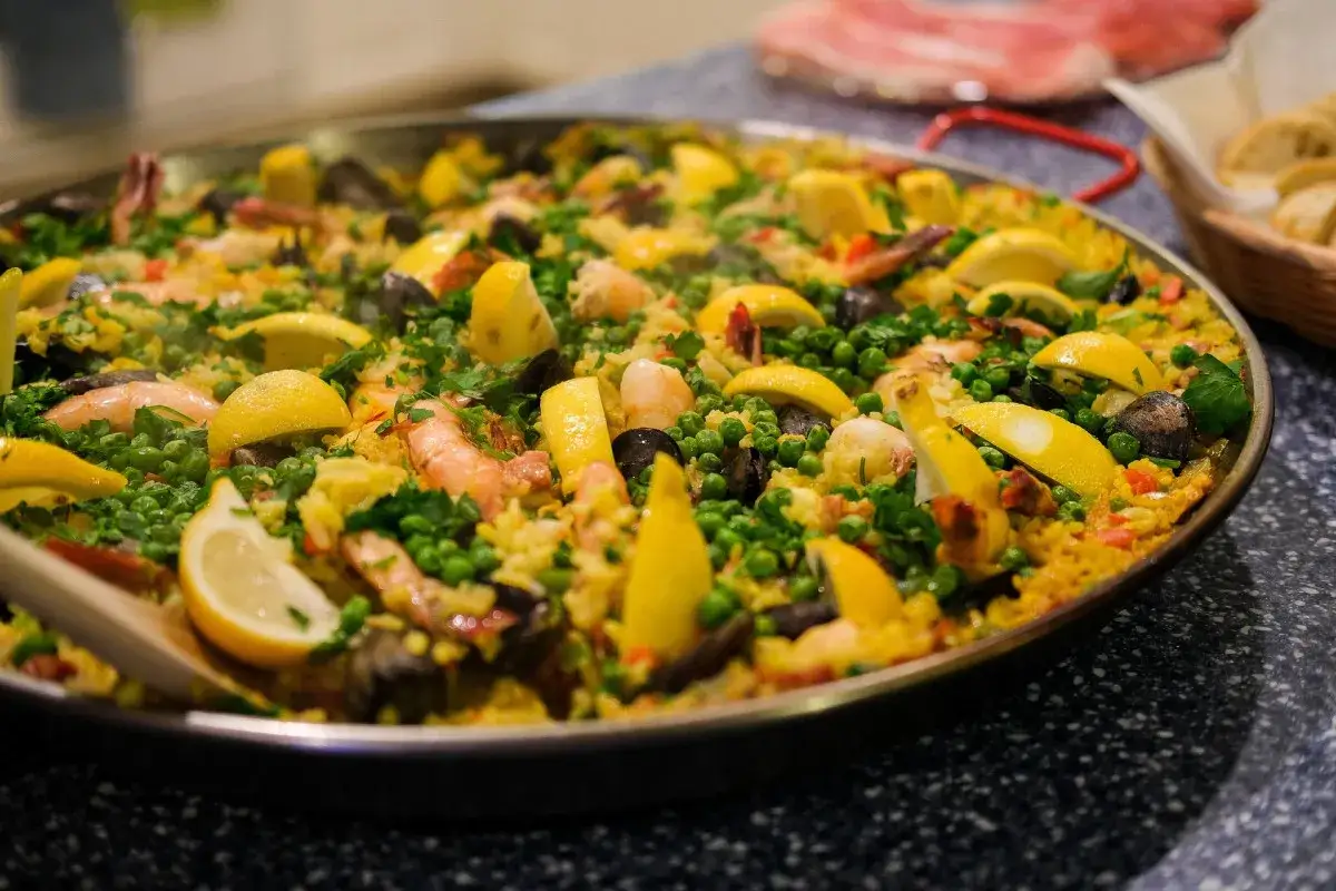 Paella z owocami morza, cytryną i groszkiem w dużej patelni.