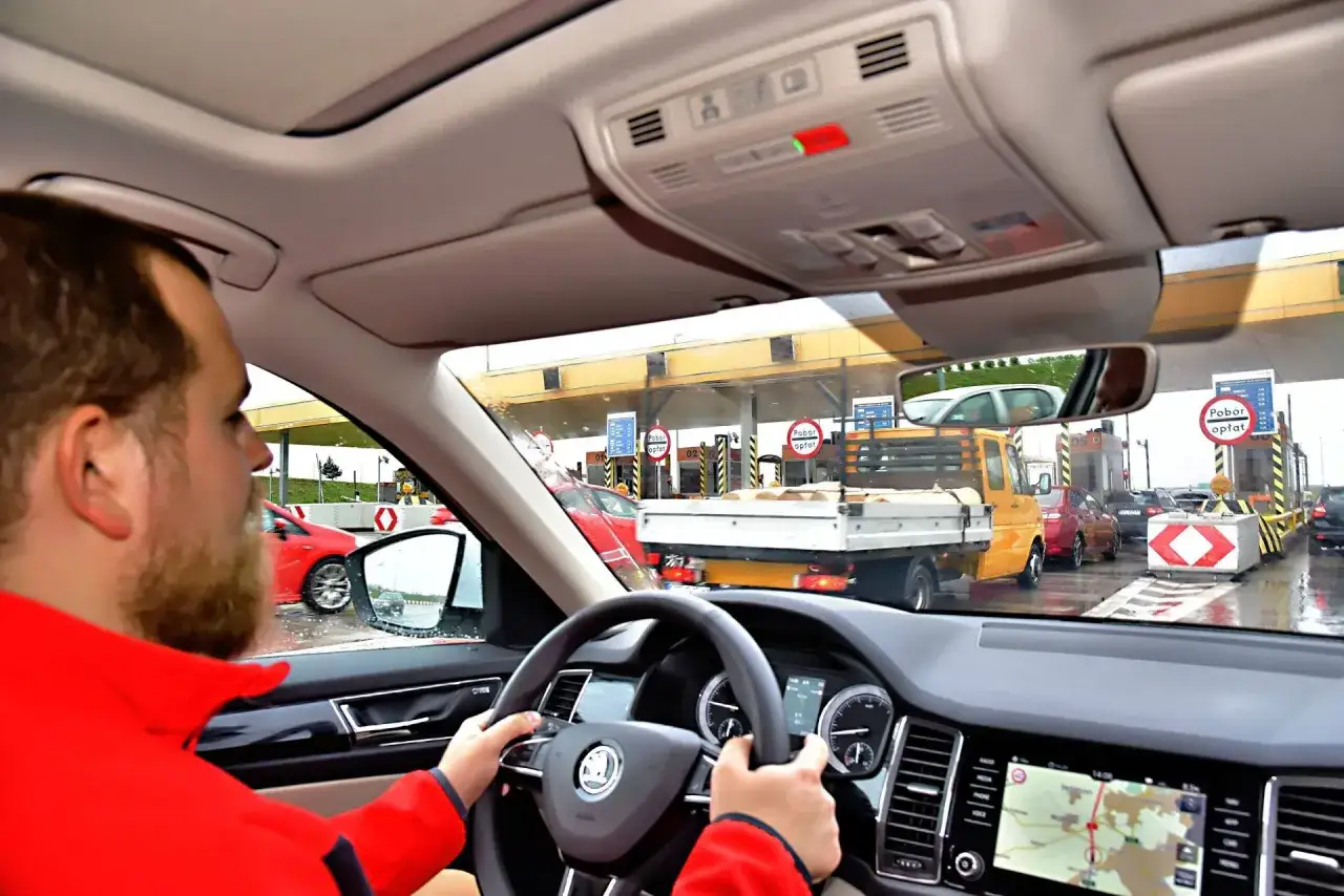 Kierowca zbliża się do bramek opłat, pokazując, jak działa system poboru opłat, podobny do tego w Blablacar.
