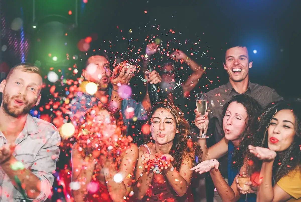 Gente celebrando con confeti y copas de champán. ¡Una fiesta perfecta para organizar despedida de soltero!