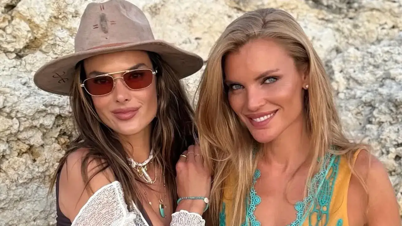 Alessandra Ambrosio y una amiga sonríen a la cámara, luciendo gafas de sol y joyas veraniegas.