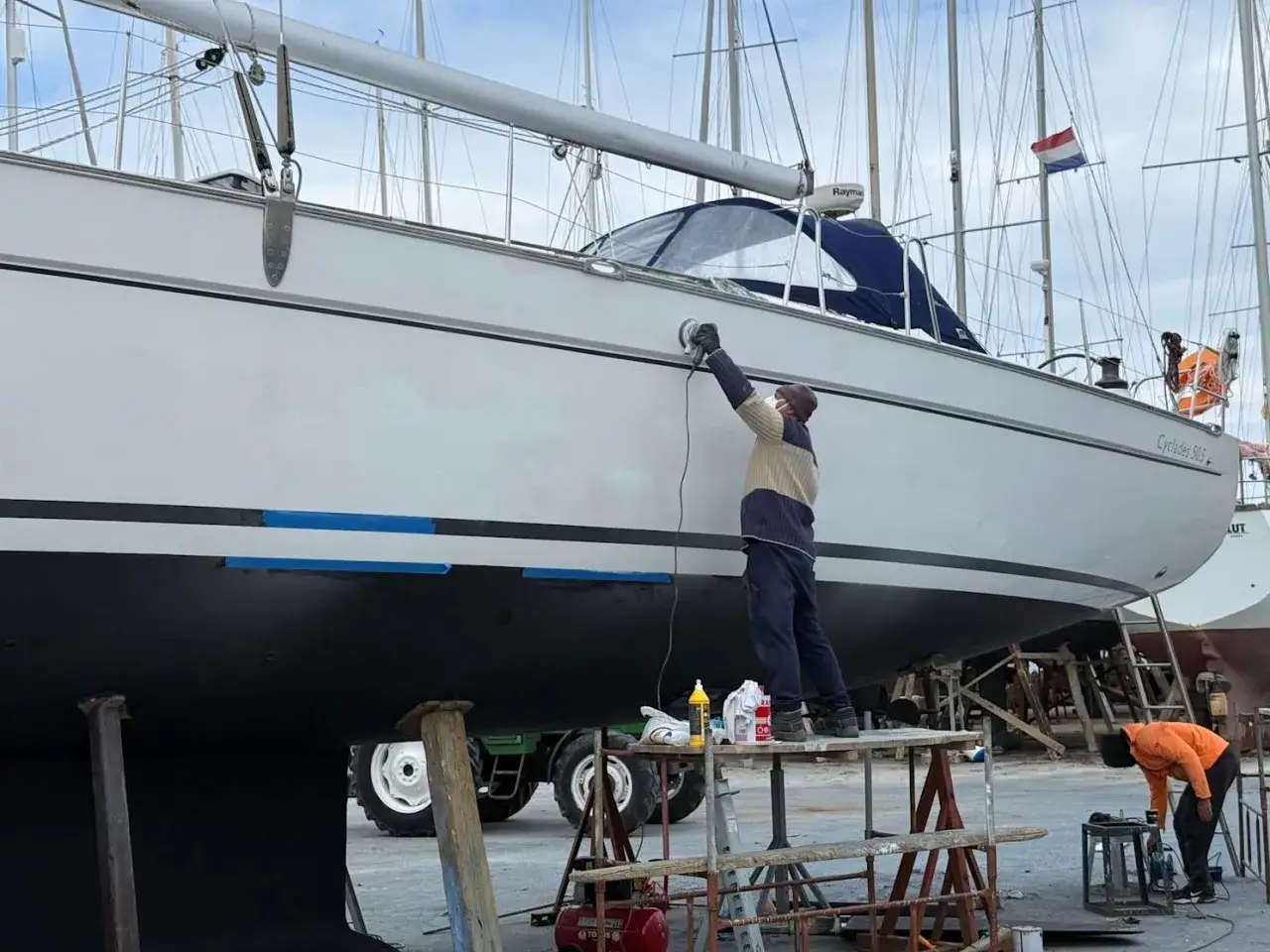 Mann poliert mit Schleifmaschine die Yacht. Edelstahl-Teile glänzen nach der Arbeit.