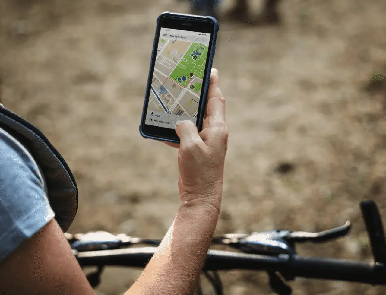 Rowerzysta sprawdza na telefonie mapę z trasą. Lokalizator GPS do roweru pomaga znaleźć drogę.