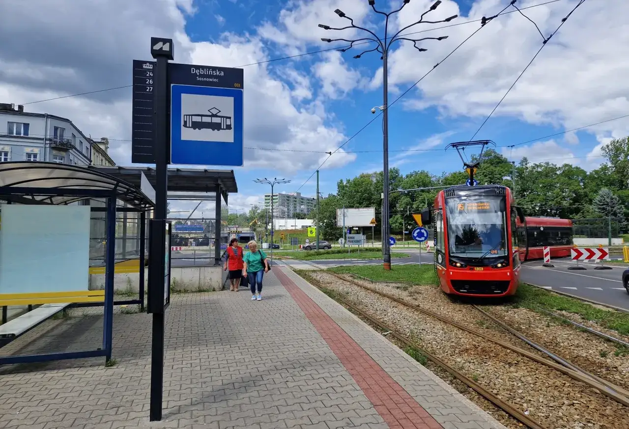 Przystanek Dęblińska w Sosnowcu. Tramwaj czeka na pasażerów, a rozkład jazdy MZK jest widoczny na słupie.