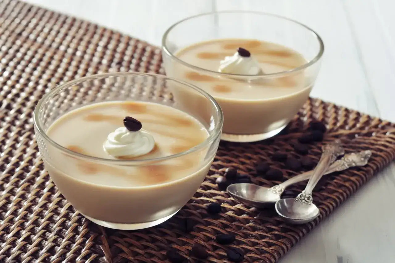 Deux verrines de crème au café façon Danette, garnies de chantilly et d'un grain de café.