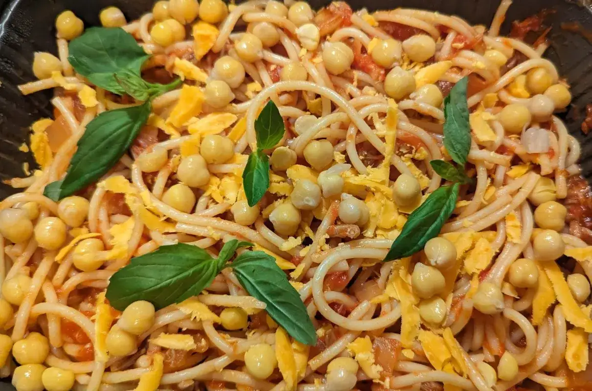 Spaghetti z ciecierzycą, startym serem i listkami bazylii.