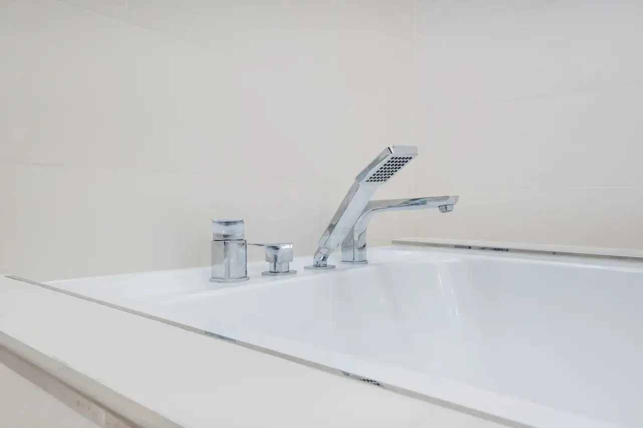 Elegancka bateria wannowa jednootworowa z chromowanymi elementami i słuchawką prysznicową, idealna do nowoczesnej łazienki.