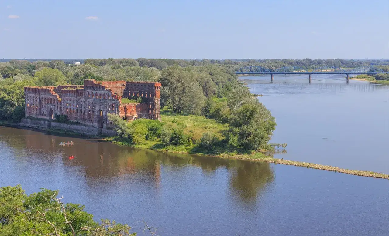 Ruiny twierdzy nad Wisłą, gdzie można poczuć się jak w górach, choć to nie są jakie góry są najbliżej Warszawy. W oddali błękitny most.