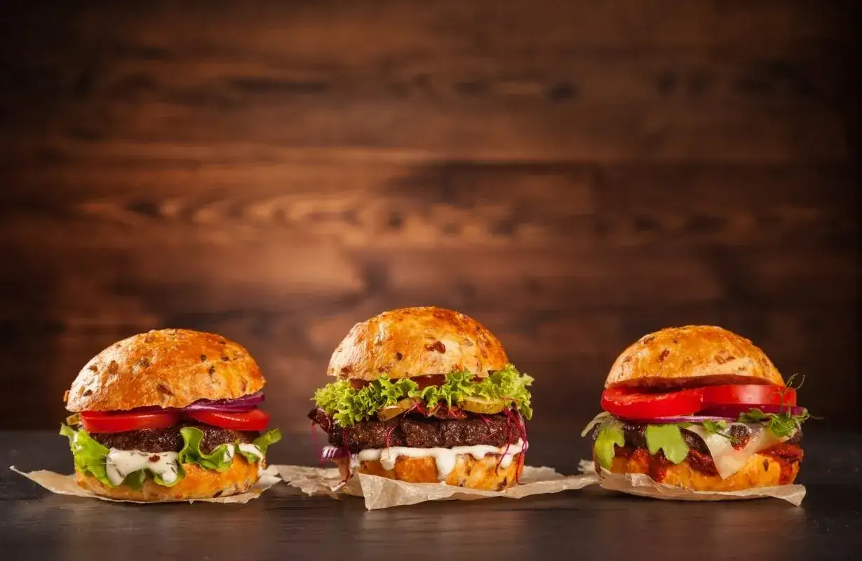 Trzy soczyste burgery z burgerowni, każdy z innymi dodatkami. Zastanawiasz się, ile kcal ma burger z burgerowni?