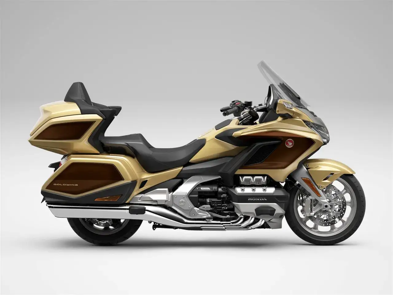 Złoty motocykl Honda Goldwing z brązowymi akcentami, gotowy na dalekie podróże.