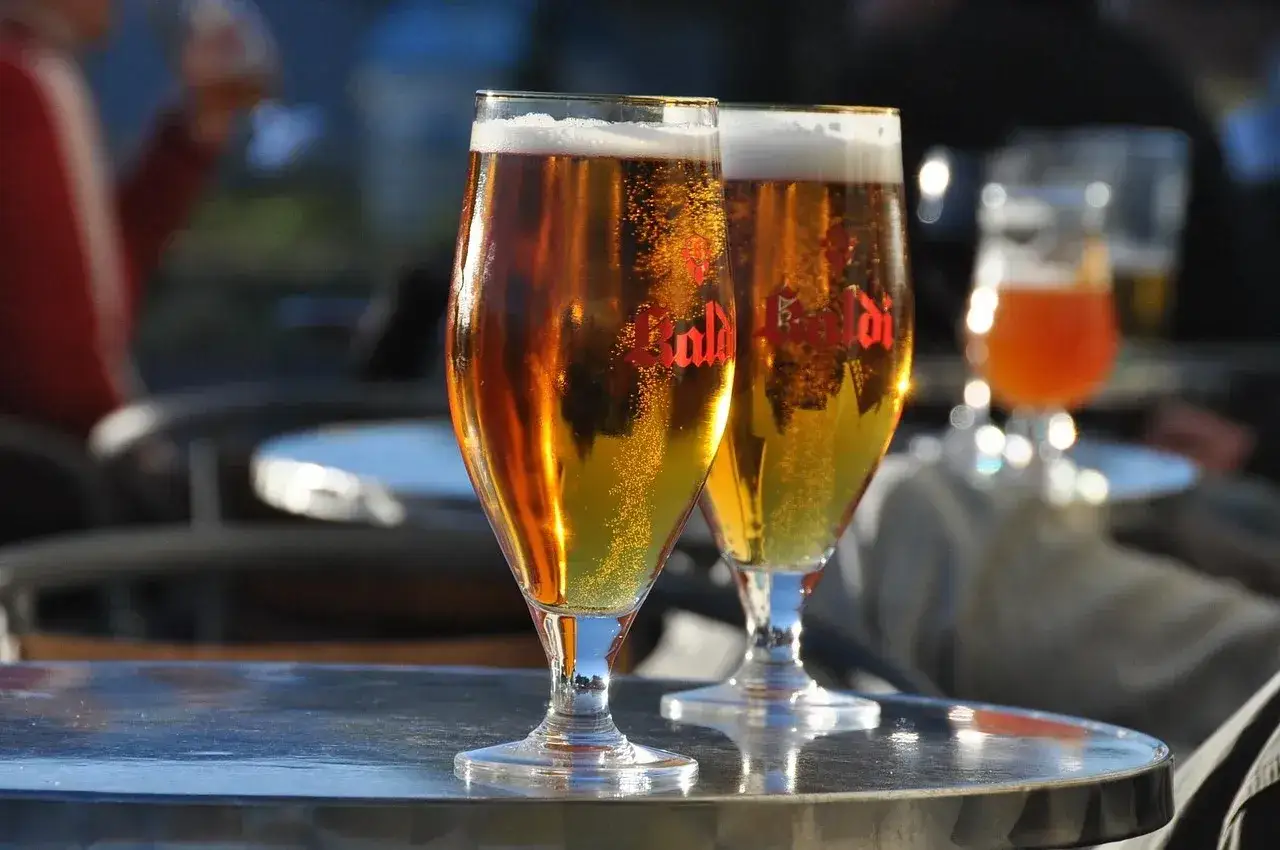 Dwa kieliszki złocistego piwa z pianką, idealne do degustacji aromatów i goryczki dzięki najlepszym technikom chmielenia na zimno (dry hopping).
