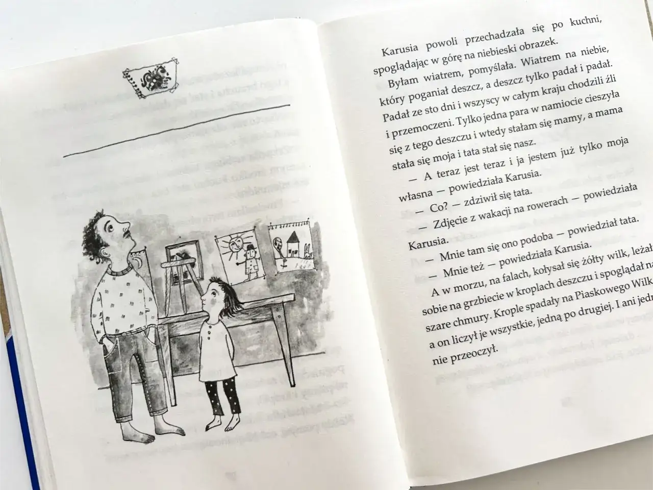 Piaskowy wilk streszczenie: Karusia z tatą oglądają rysunki. Jeden przedstawia wilka liczącego krople deszczu.