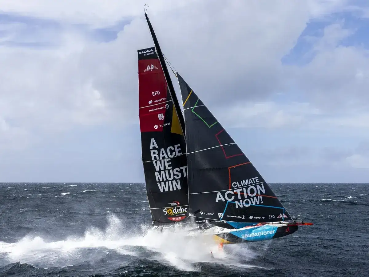 Segelboot mit der Aufschrift "A RACE WE MUST WIN" und "CLIMATE ACTION NOW!" auf dem Weg zum Vendée Globe.