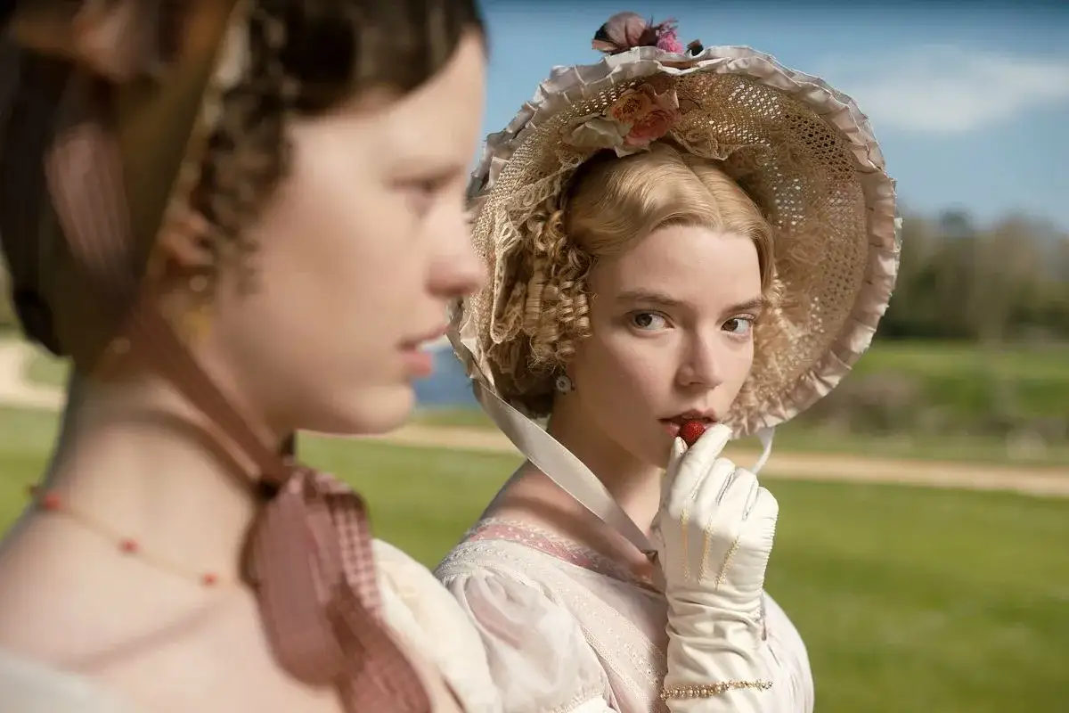 Emma, z powieści Jane Austen, w białej rękawiczce wkłada truskawkę do ust.