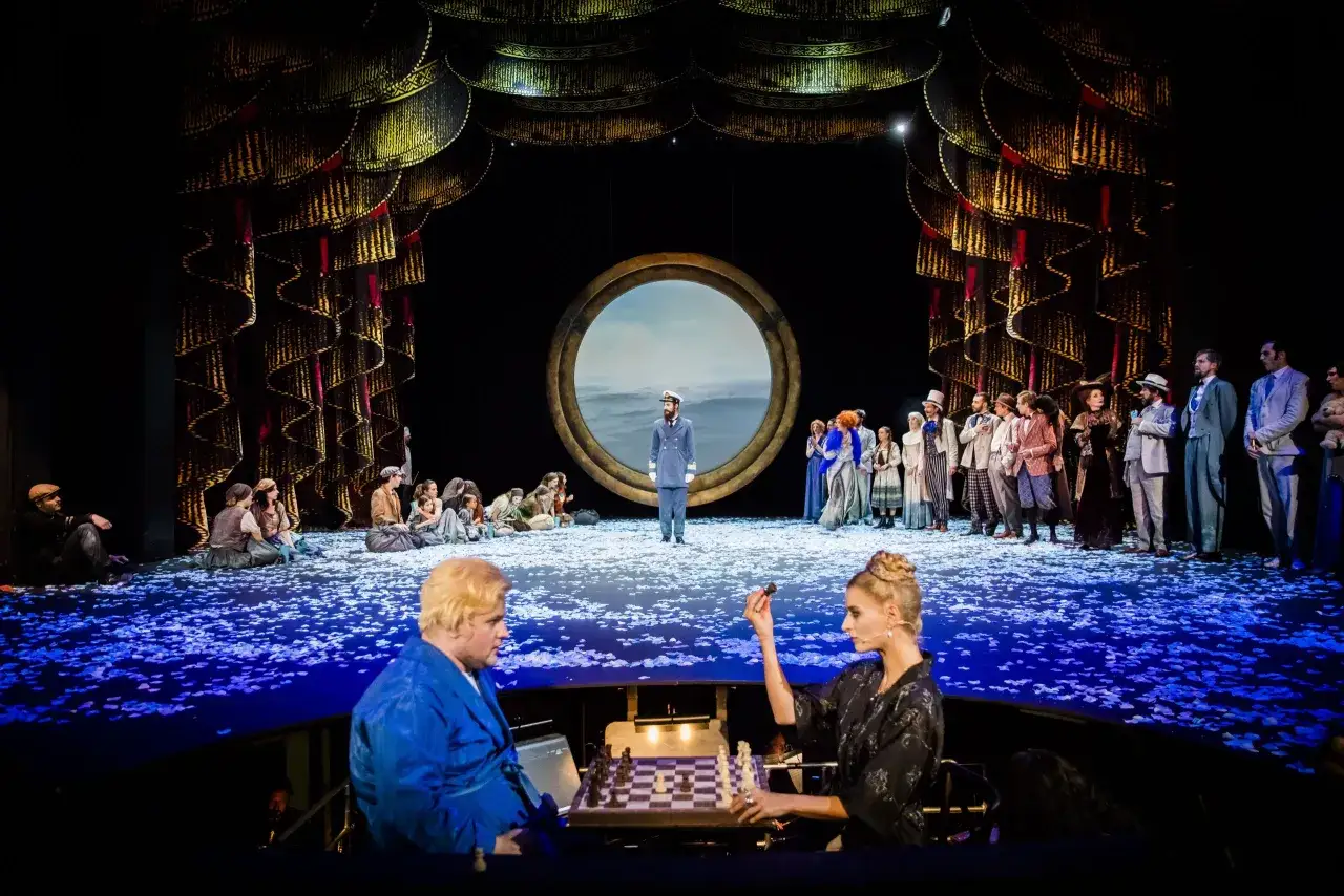 Na dużej scenie Teatru Capitol trwa spektakl. Aktorzy w strojach z epoki, wśród nich kapitan, siedzą na scenie usypanej płatkami.