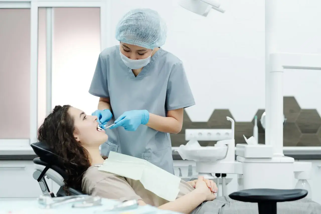 Dentystka bada zęby pacjentki, szukając oznak problemów, które mogą wymagać leczenia kieszonek dziąsłowych.