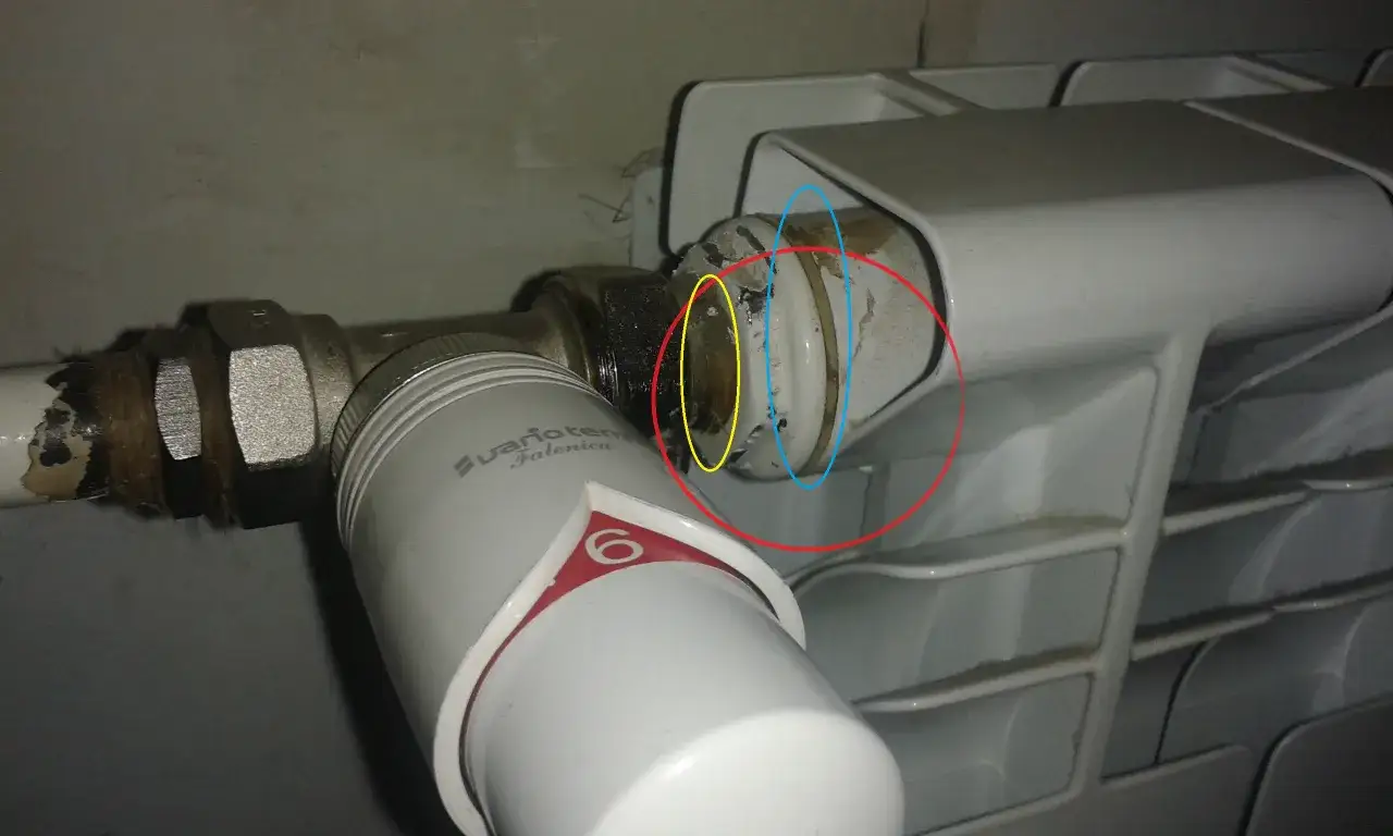 Uszczelnienie cieknącego grzejnika: widoczny zawór termostatyczny i miejsce połączenia z grzejnikiem, które wymaga naprawy.