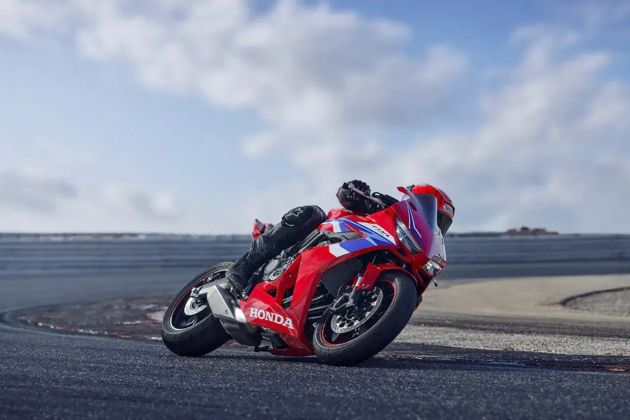 Czerwony motocykl Honda CBR650R z kierowcą pochylonym na zakręcie toru wyścigowego.