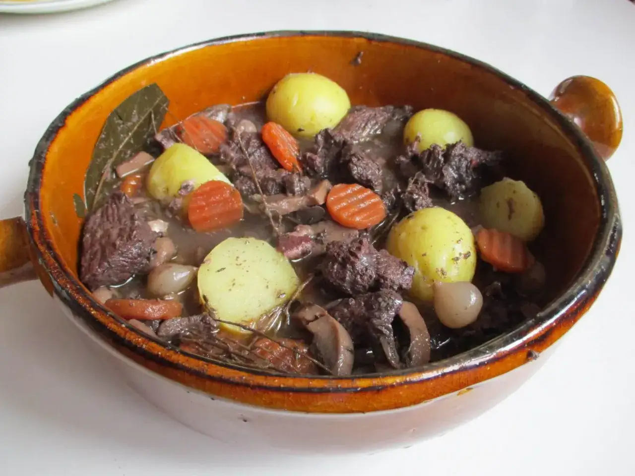 Un plat mijoté, spécialité culinaire Provence, avec du bœuf, des carottes, des pommes de terre et des oignons dans un jus savoureux.
