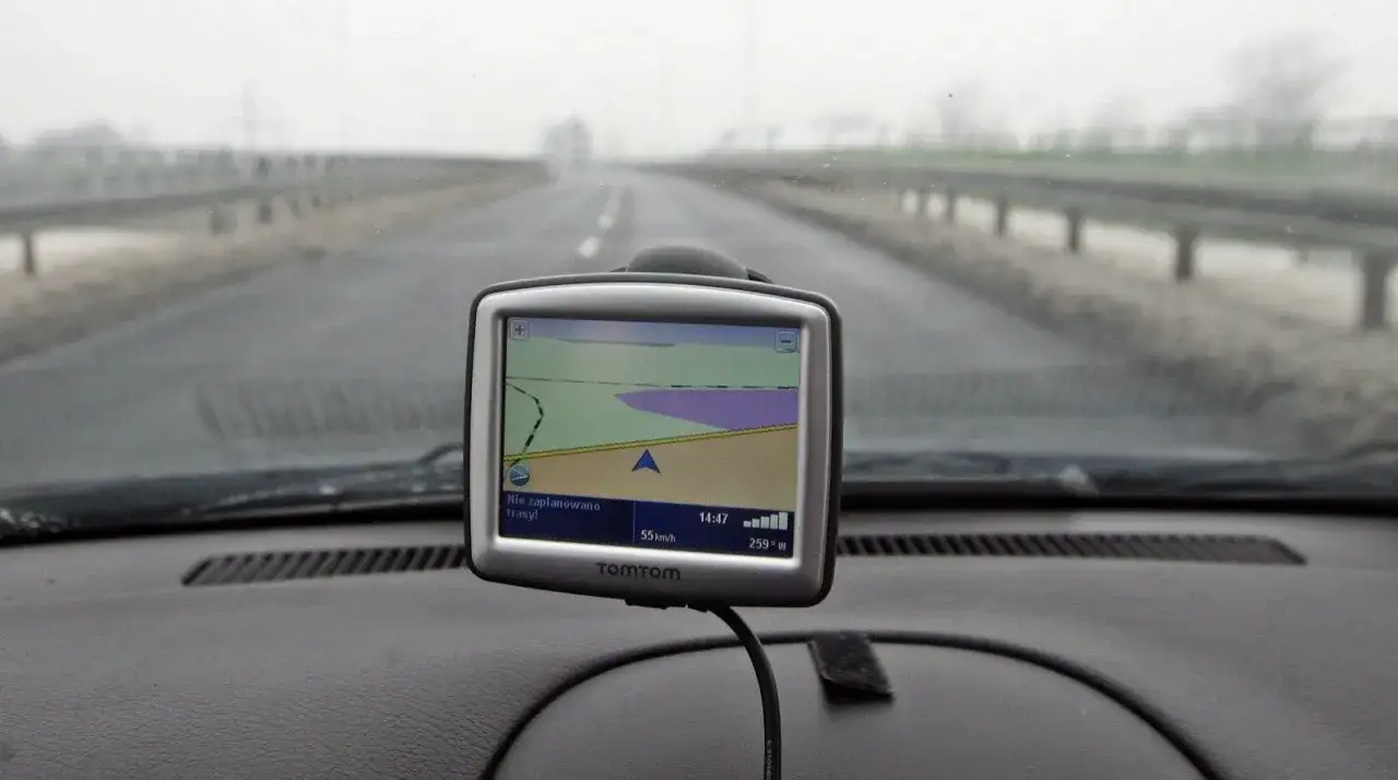 Nawigacja TomTom na desce rozdzielczej samochodu podczas jazdy w mglisty dzień.