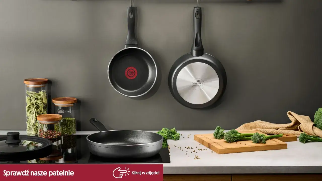 Dwie patelnie wiszą na ścianie, jedna z logo Tefal. Czy patelnie Tefal można myć w zmywarce? Na blacie leżą brokuły i przyprawy.