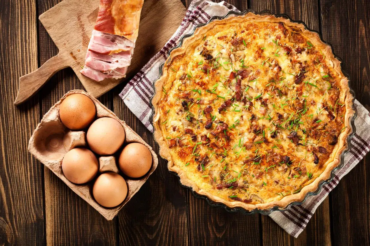 Quiche Lorraine, un classique de la gastronomie lorraine, avec ses ingrédients frais : œufs, lardons et herbes.