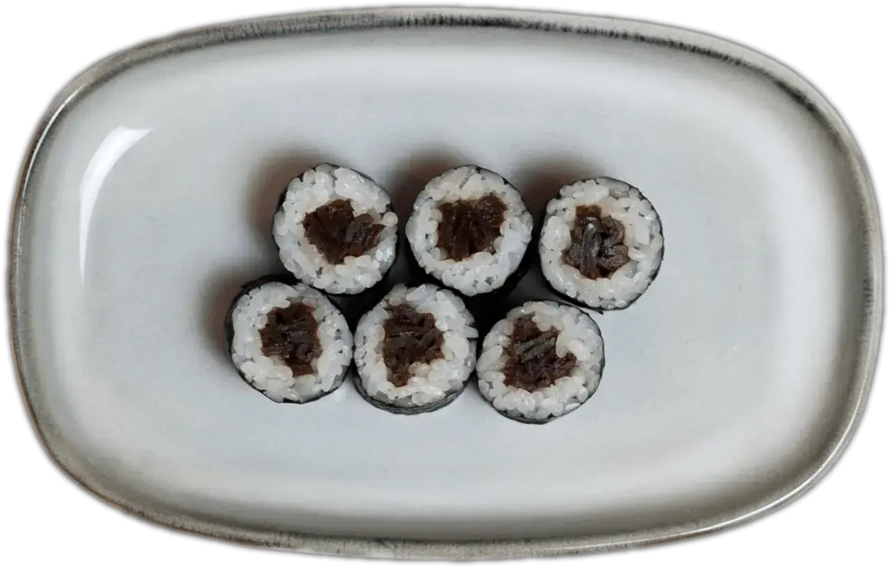 Sześć kawałków sushi z ryżem i ciemnym nadzieniem na szarej tacy.