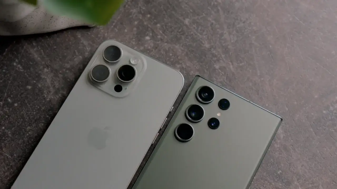 Dwa najnowsze fotosmartfony, iPhone i Samsung, leżą obok siebie na ciemnym tle.