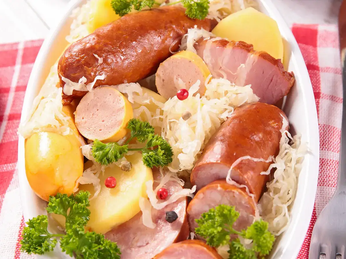 Assiette garnie de choucroute, saucisses, pommes de terre et lard, un plat typique des alsace spécialités culinaires.