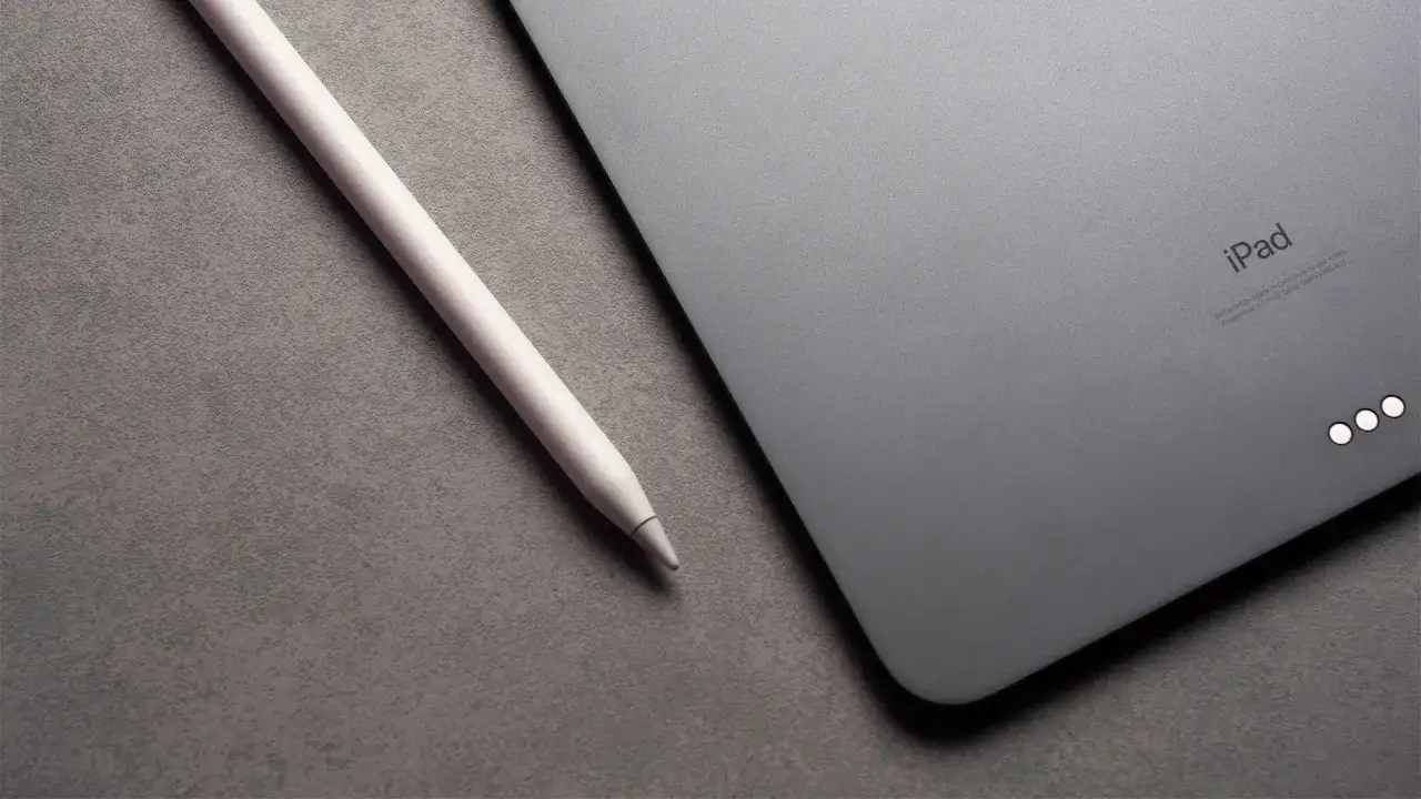 Apple Pencil liegt neben einem iPad mit drei leuchtenden Punkten.