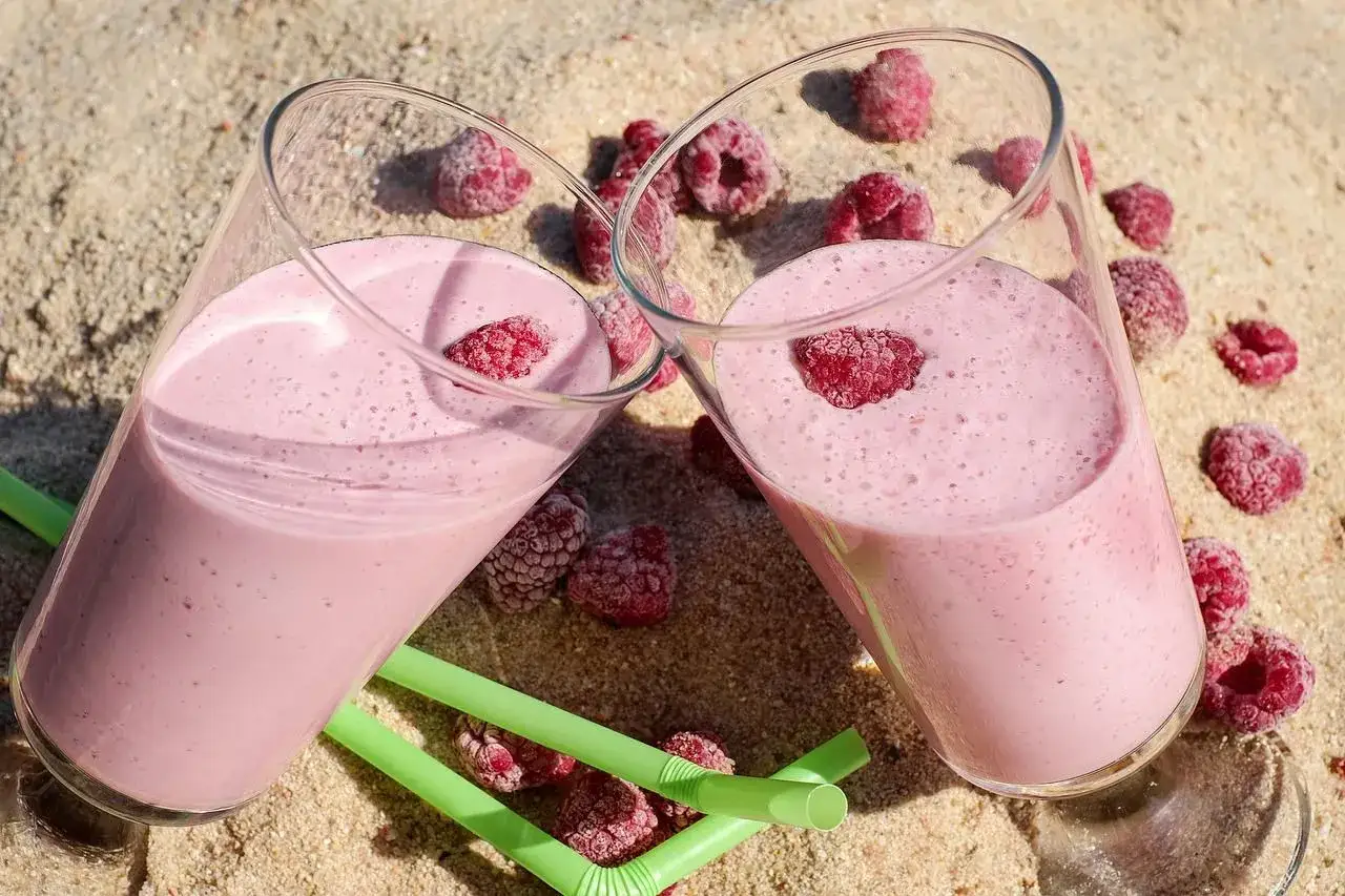 Dwa pyszne malinowe smoothie na piasku, idealne na lato. Inspiracja na zdrowe smoothie przepisy.