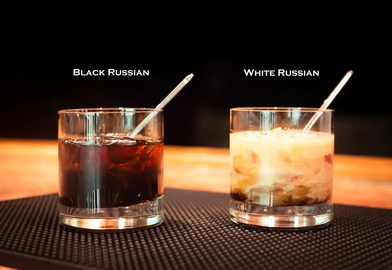 Dwa drinki: ciemny Black Russian z lodem i jasny White Russian z mlekiem, każdy w szklance z rurką.