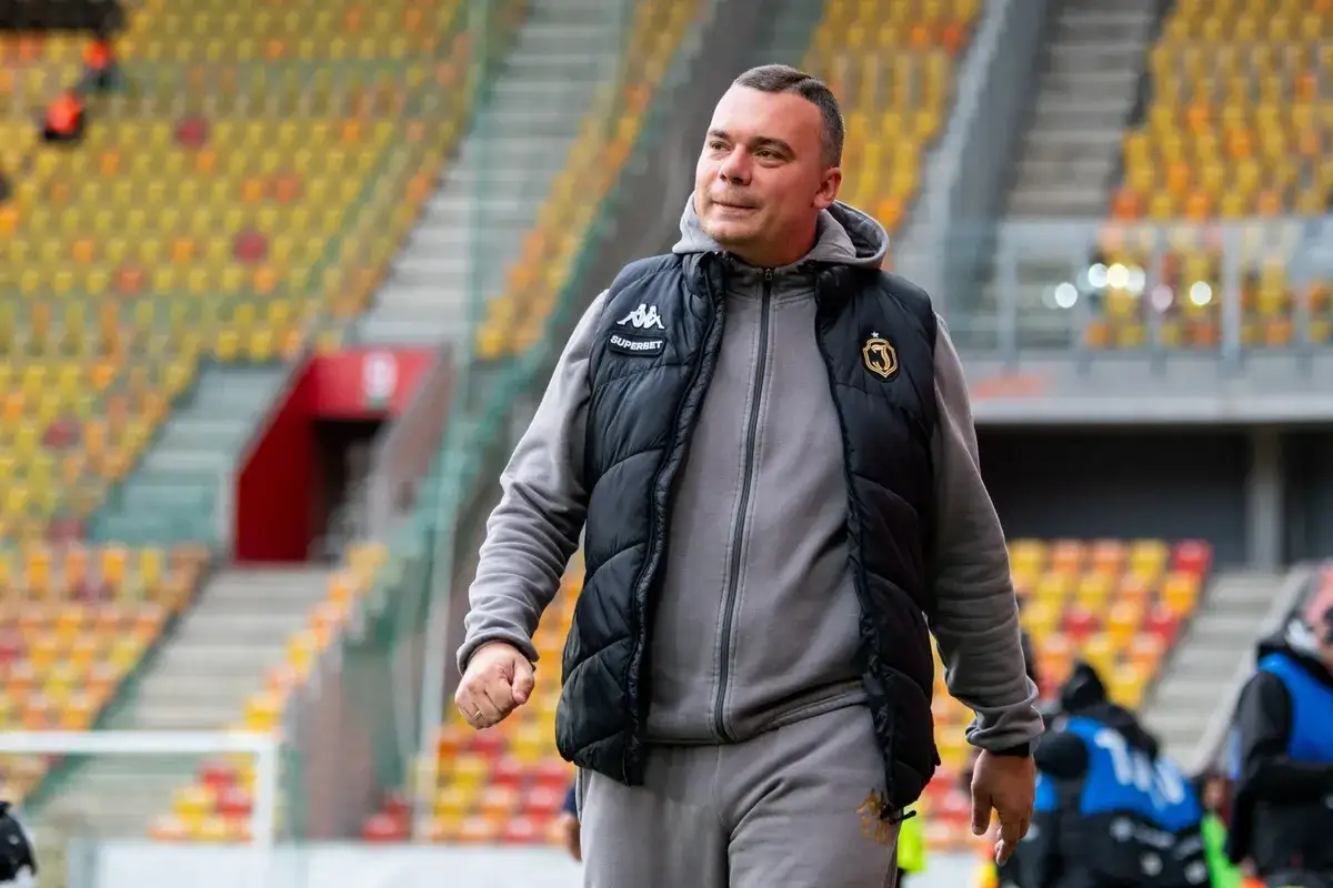 Mężczyzna w kamizelce Jagiellonii, być może omawia nowe jagiellonia transfery na tle pustych trybun stadionu.