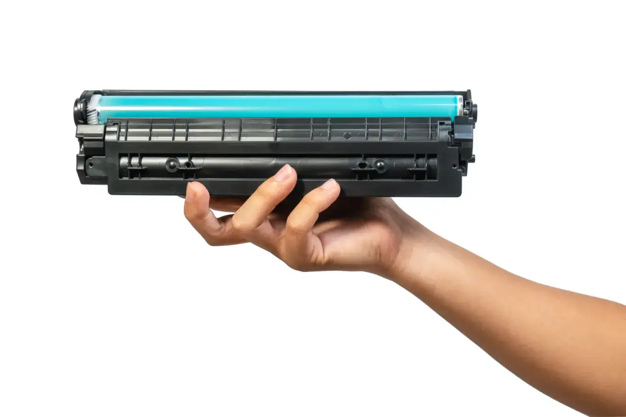 Dłoń trzymająca toner do drukarki HP. Dowiedz się, jak wymienić tusz w drukarce HP, aby cieszyć się wydrukami.