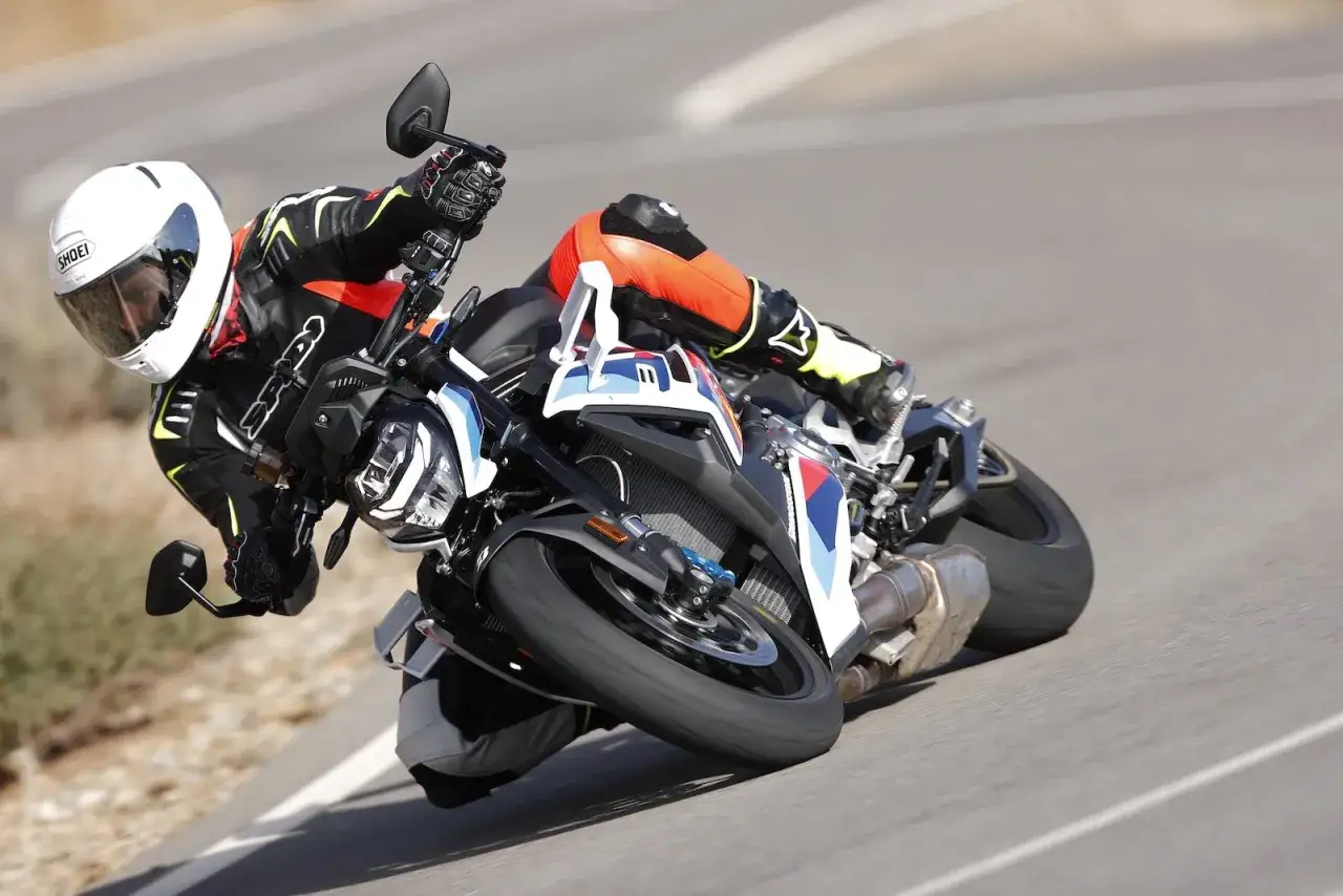 Motocyklista w kombinezonie i kasku pochyla się na zakręcie na sportowym motocyklu BMW. DTC BMW zapewnia kontrolę.