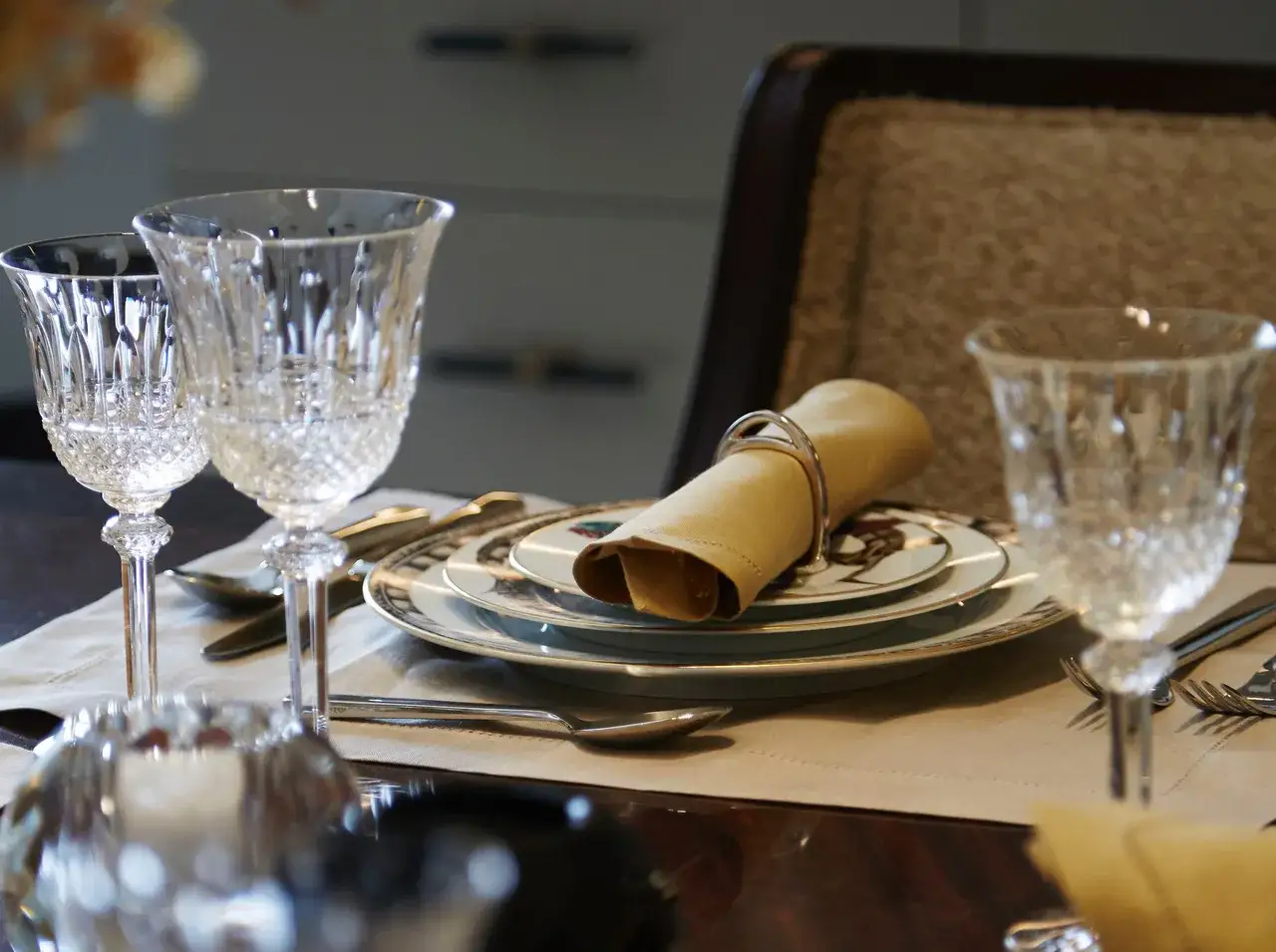 Verre à pied taillé, assiettes décorées, serviette en tissu joliment pliée : une table dressée pour le service à la française.