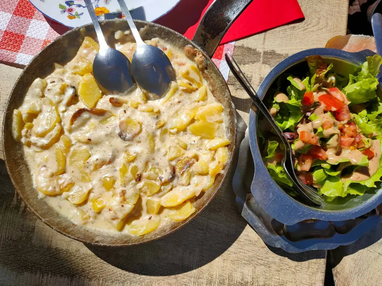 Plat de pommes de terre crémeuses, une spécialité auvergnate, servi dans une poêle avec une salade fraîche.