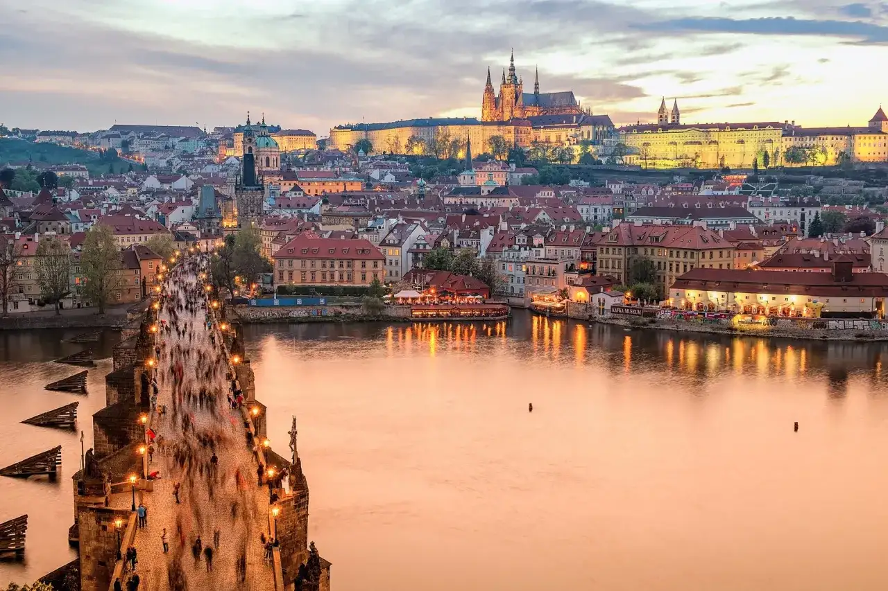 Zachód słońca nad Pragą, tłumy na Moście Karola. Czy do Czech trzeba mieć paszport? Nie, wystarczy dowód osobisty.