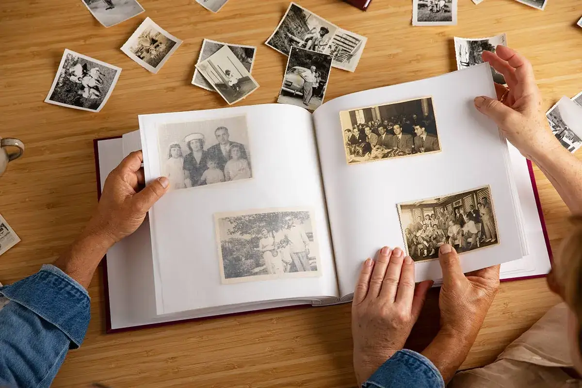 Manos hojeando un álbum de fotos antiguas, reviviendo recuerdos. Quizás buscando frases 50 aniversario para acompañar estas imágenes.