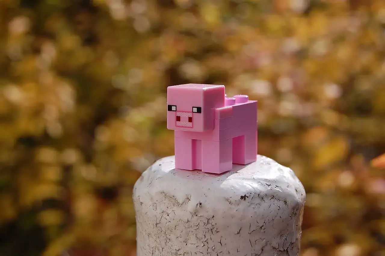 Różowa świnka z klocków Minecraft na białym postumencie. Może to być inspiracja do najlepszych modów do Minecraft, które dodają nowe zwierzęta.
