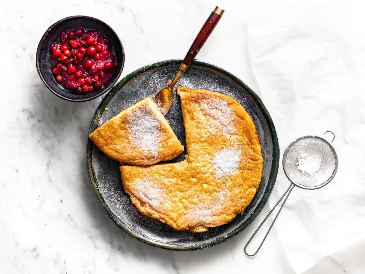 Puszysty omlet z air fryera, posypany cukrem pudrem, podany z żurawiną. Idealny na śniadanie.