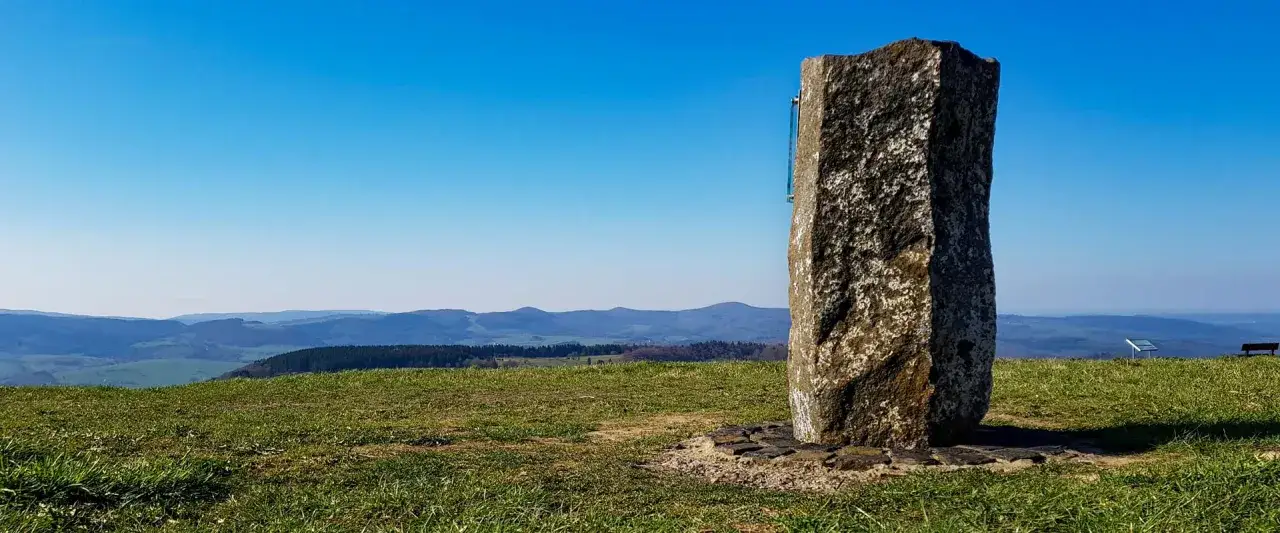 Steinerner Gedenkstein auf der Wasserkuppe mit Blick über Hügel und Täler.